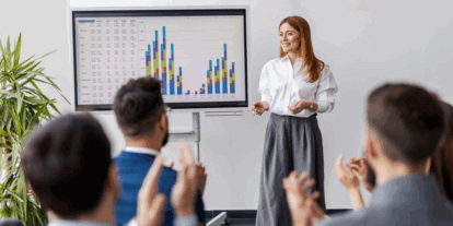 Junge Frau hält eine Präsentation vor einem Bildschirm mit Balkendiagrammen, während das Publikum applaudiert.; Continue to the article "Good stress only"