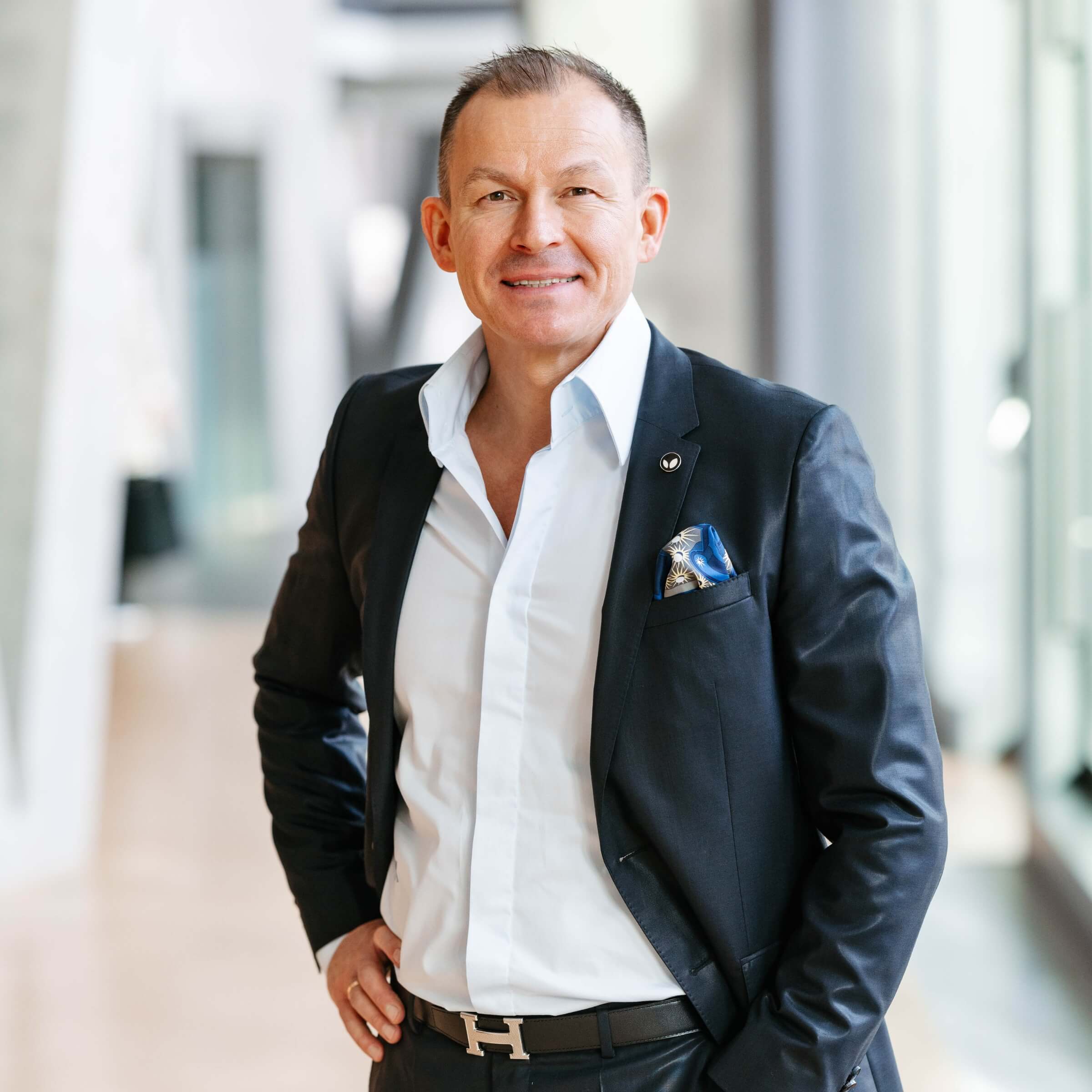 Andrej Uschakow, Co-Founder und Chief Sales Officer der hajoona GmbH, steht in einem modernen Bürogebäude und blickt freundlich in die Kamera.